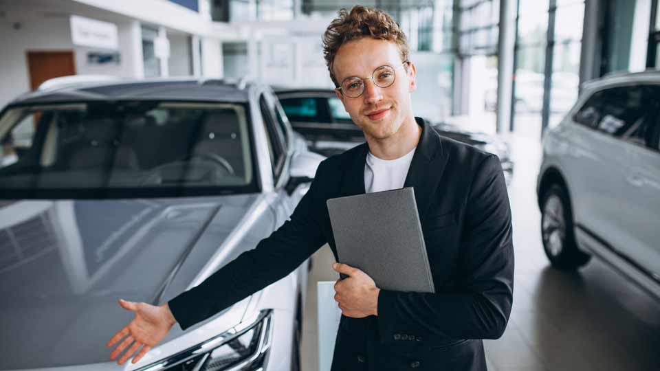 Ein Verkäufer zeigt auf ein Auto und erklärt dem Kunden die Konditionen beim Auto verkaufen Bautzen